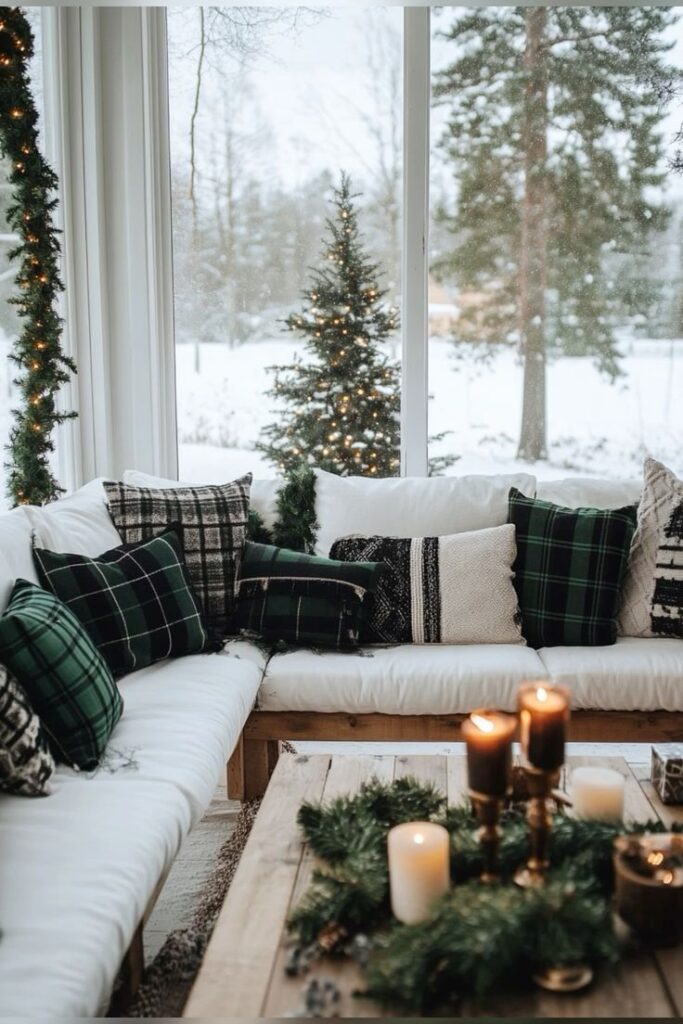 fb05d2d9-951f-4aba-9d18-1b22328b5316 - Handy Home Cozy winter living room with plaid pillows, candles, and festive decor. Snowy window view with twinkling Christmas tree lights.