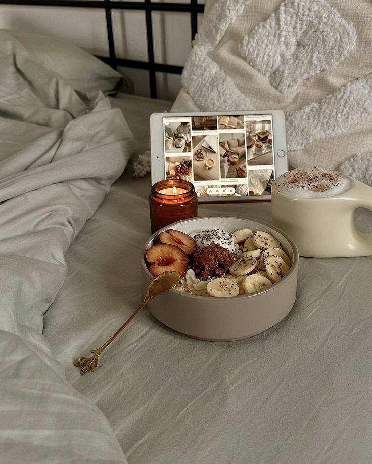 gxfnzd - Handy Home Cozy breakfast in bed: oatmeal with banana and plum slices, candlelight, and latte on a tablet-viewing day.