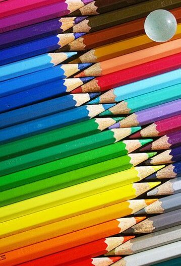 harmony - Handy Home Colorful arrangement of pencils with a glass marble on top, showcasing vibrant hues in a diagonal pattern.