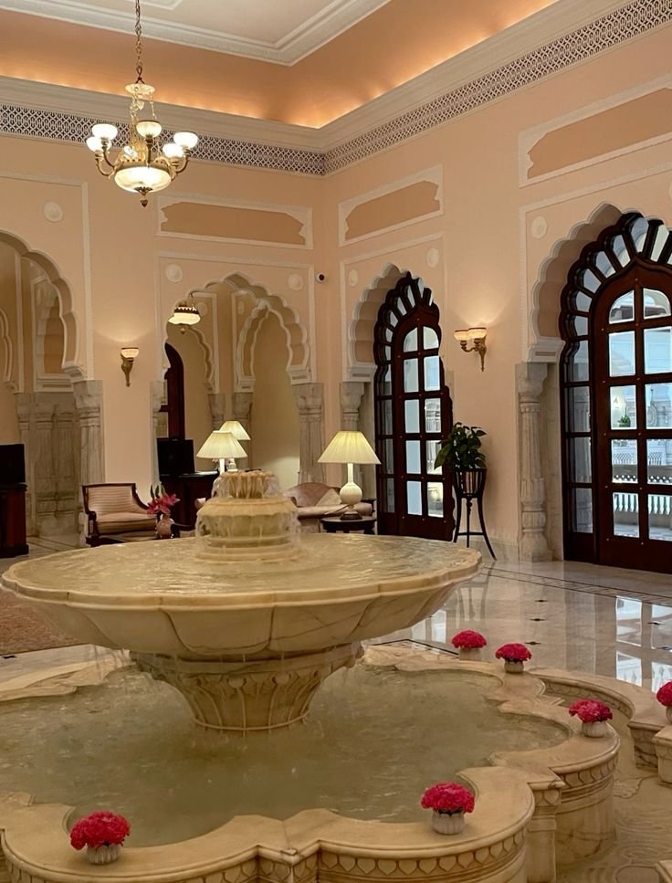 Elegant hotel lobby with ornate marble fountain, arched doorways, and soft lighting. Luxurious atmosphere and classic decor.