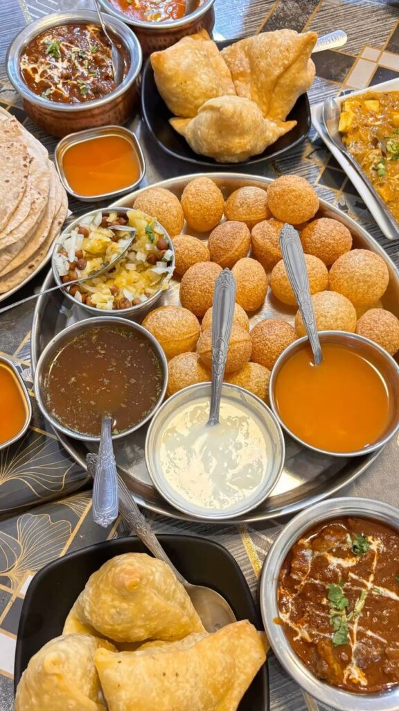 indian food _3 - Handy Home Traditional Indian thali with samosas, puris, curries, chutneys, and papadums. A vibrant, flavorful feast on the table.