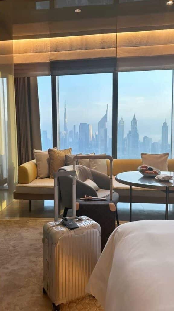 Luxurious hotel room with city skyline view, suitcase ready for travel; perfect for business or leisure stays.