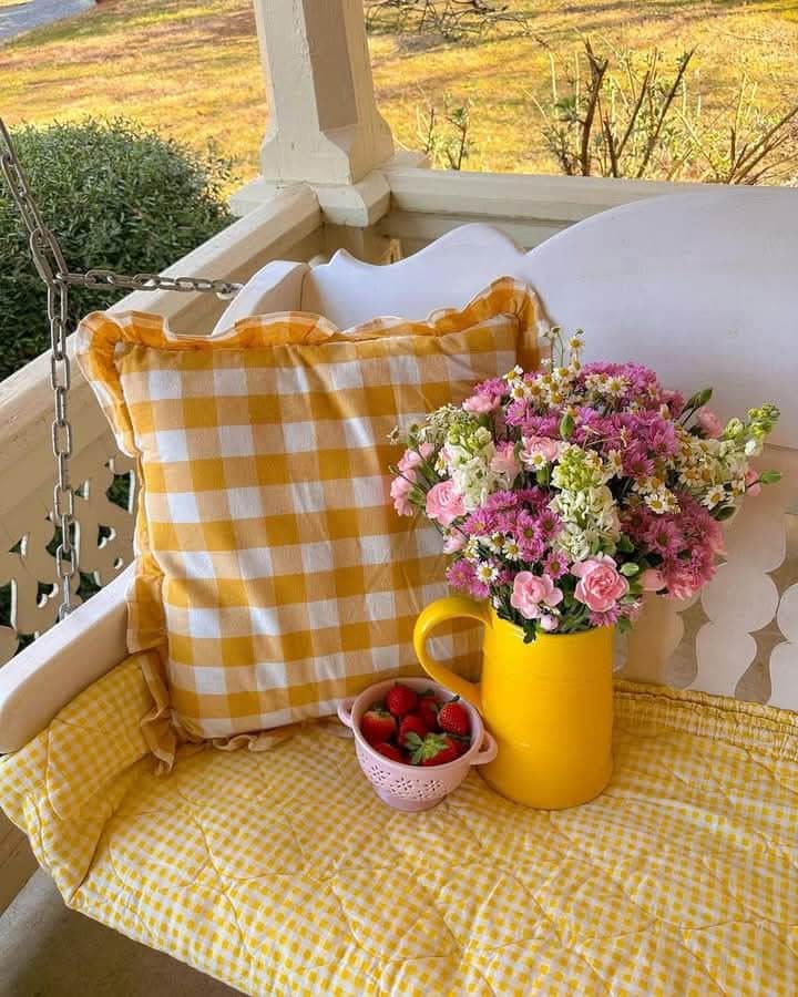 rgaer - Handy Home Cozy porch swing with a yellow checkered pillow, flowers in a yellow vase, and a pink bowl of strawberries.