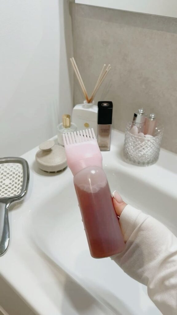 rosemary water for hair 💕 haircare hairgoals - Handy Home Hand holding hair dye bottle with brush tip in modern bathroom setting, ready for application.
