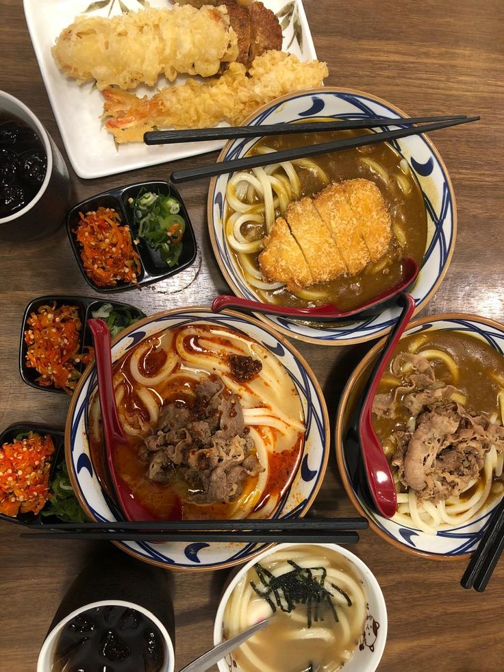 udon - Handy Home Assorted Japanese udon dishes and tempura on a wooden table, accompanied by toppings and cold drinks.