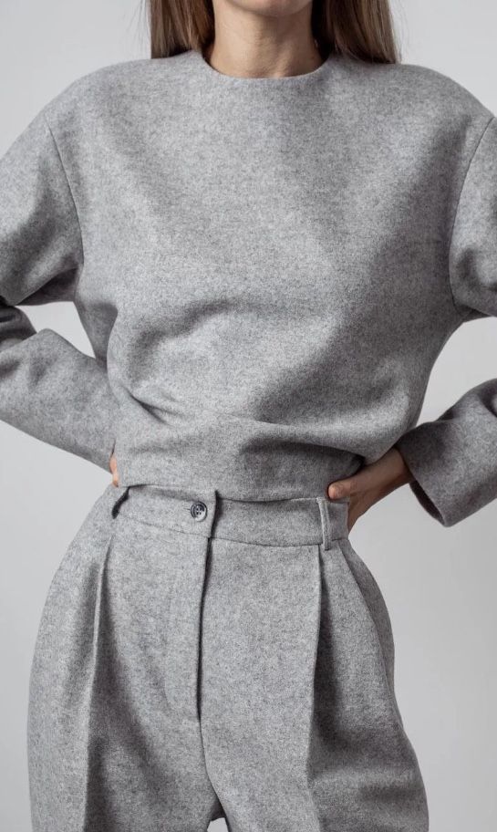 Woman wearing a stylish gray wool suit, featuring a boat neck top and high-waisted trousers.