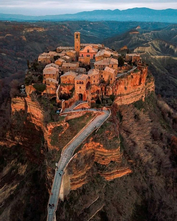 undefined 1 - Handy Home Aerial view of Civita di Bagnoregio, Italy, perched on a hilltop, surrounded by scenic valleys and rugged terrain.