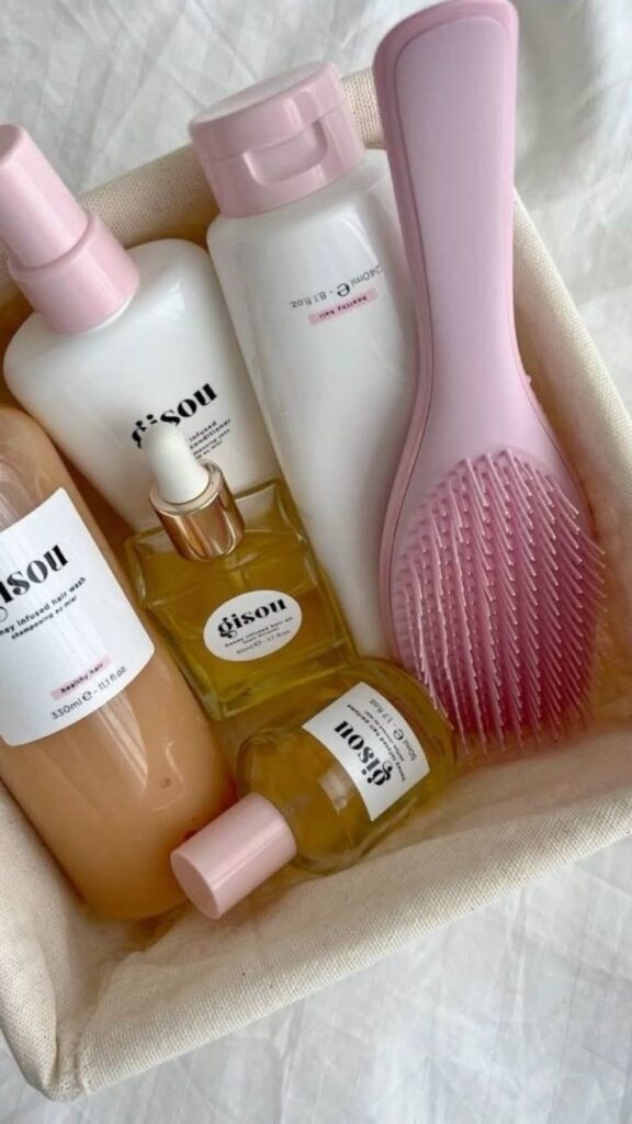 zgbS - Handy Home Basket with hair care essentials: shampoo, conditioner, oil bottles, and a pink detangling brush on a soft fabric background.