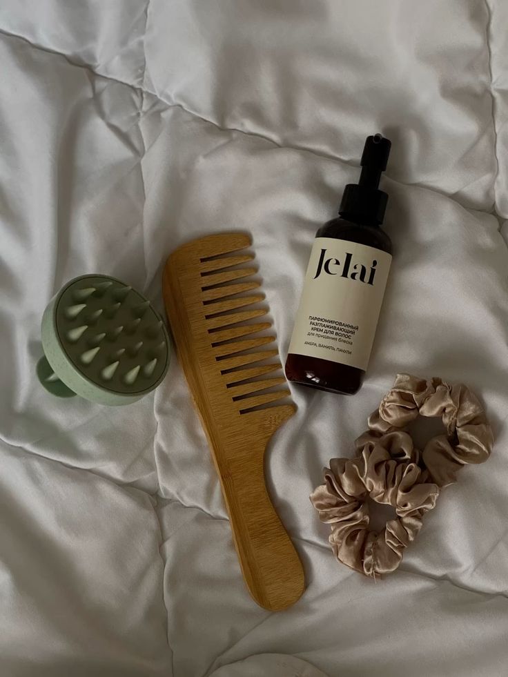 Девачьи штучки - Handy Home Hair care essentials on a white surface: wooden comb, hair spray, scalp massager, and beige scrunchies for styling and maintenance.