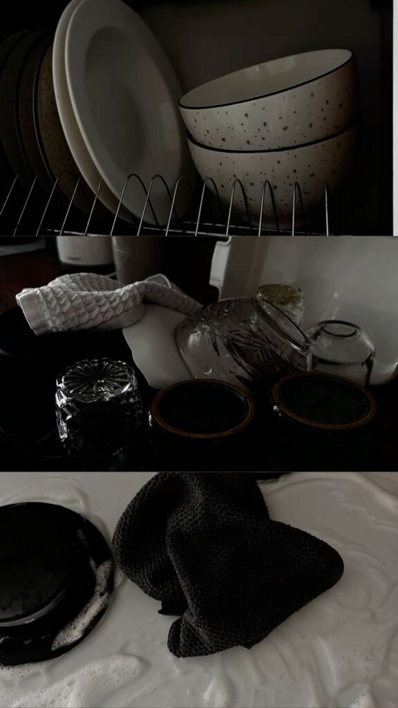Clean dishes stacked on a rack, drying cloth, and soapy black dish in a kitchen sink cleaning scene.