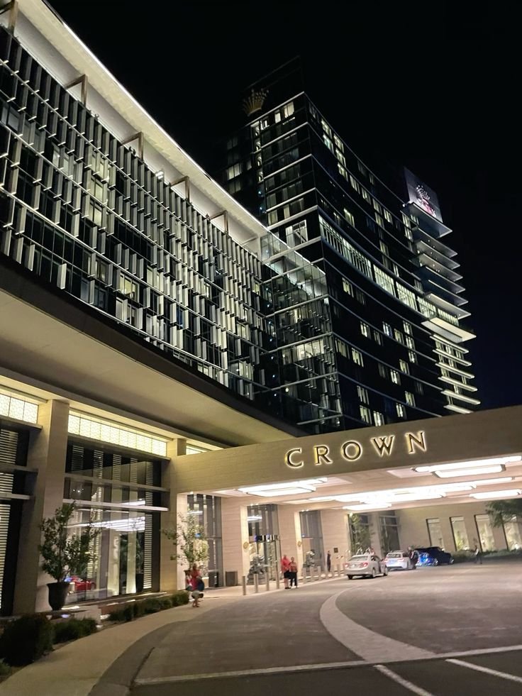 Elegant night view of Crown hotel entrance with modern architecture and illuminated facade. Luxury destination ambiance.