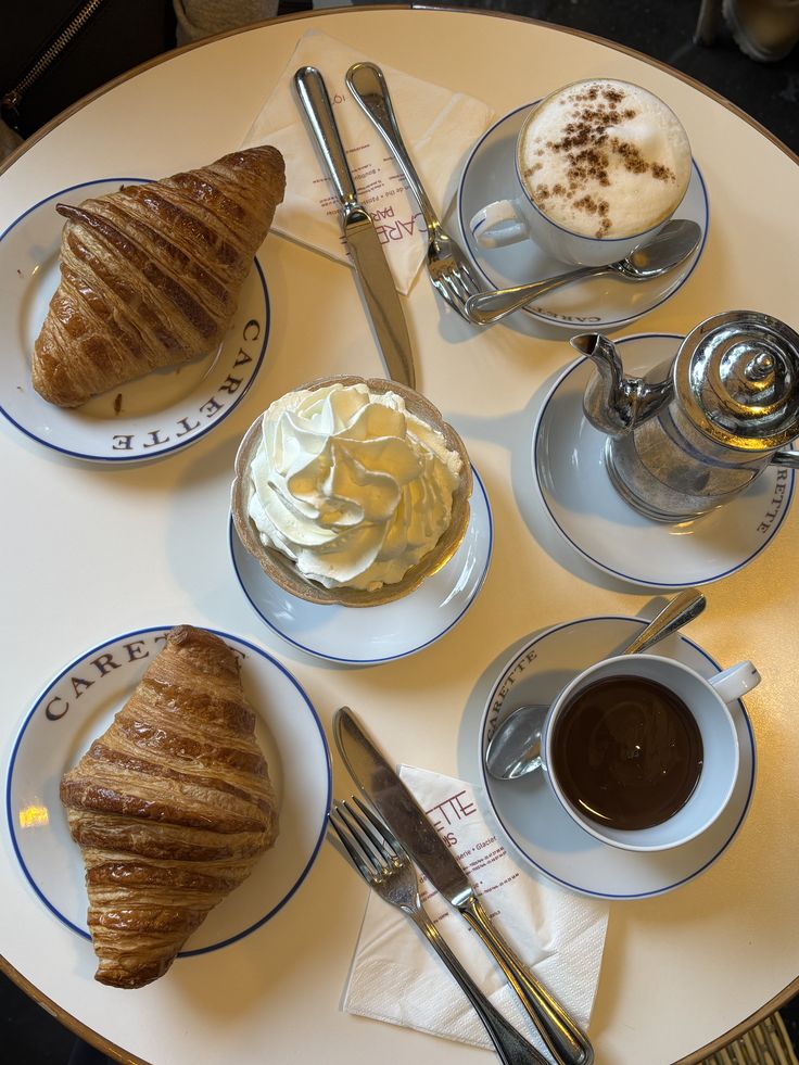 🥐 - Handy Home French breakfast with croissants, coffee, and whipped cream on a cafe table. Perfect Parisian start to the day at Carette.
