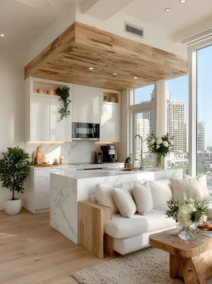 10 First Apartment Essentials_ Your Ultimate Checklist for Setting Up Your New Digs - Handy Home Modern kitchen with marble island, wooden ceiling, and cozy seating area. Bright and airy space featuring city views and greenery.
