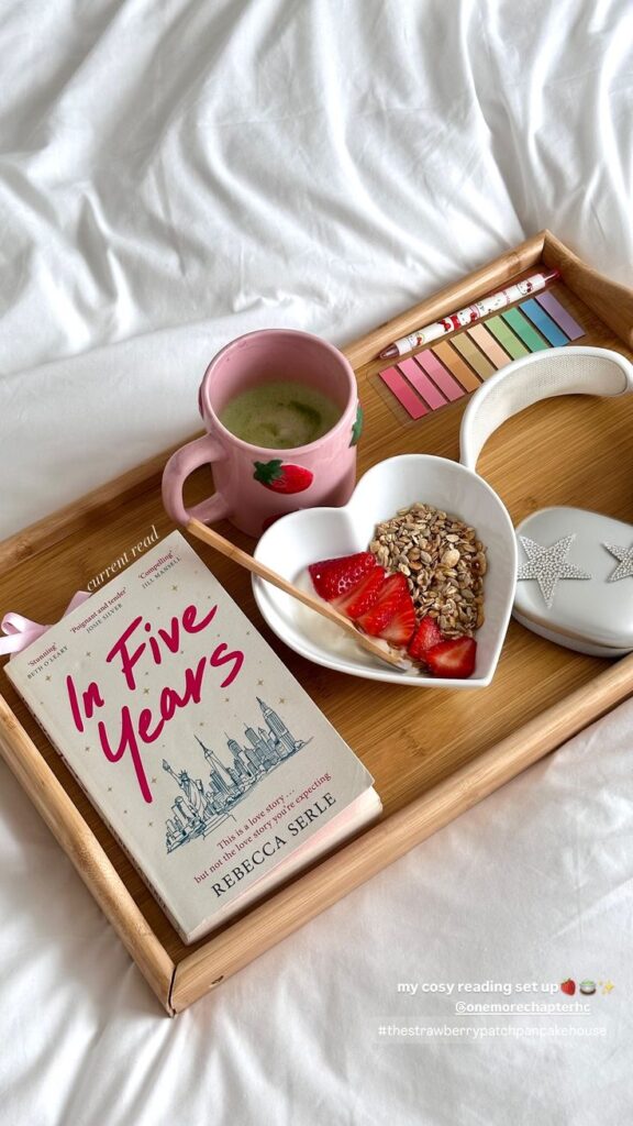 163b3cd3-3588-4c1a-a299-abee4605ecf5 - Handy Home Cozy setup with book In Five Years, a strawberry mug, and granola bowl on a wooden tray. Perfect for a relaxing reading session.