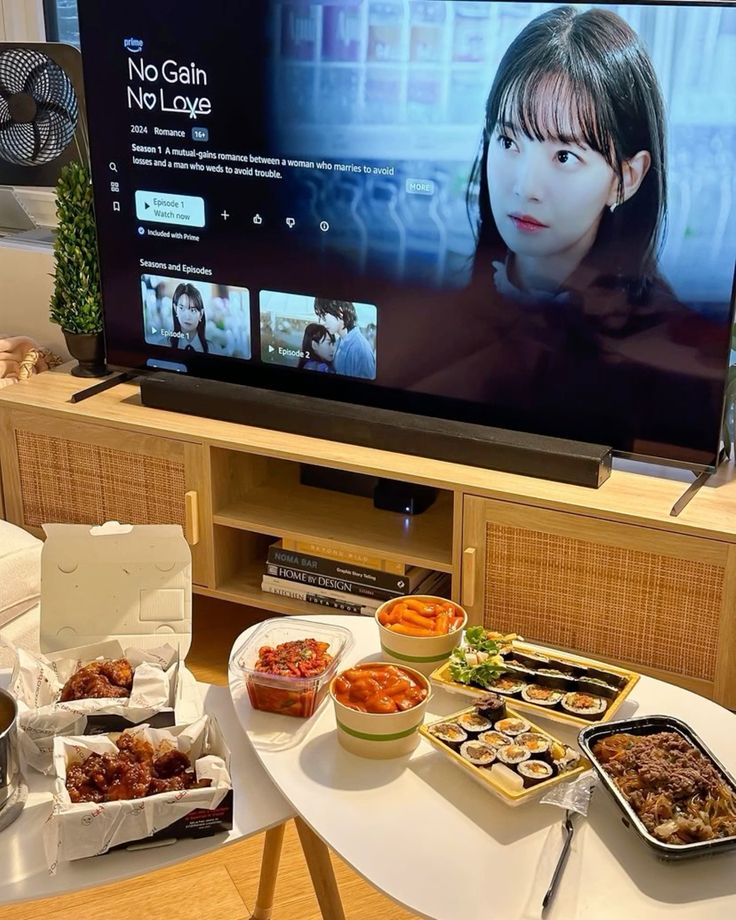 2d555995-fe70-46cd-88fe-bcd7b79d0506 - Handy Home TV streaming show with Korean food spread: fried chicken, kimchi, tteokbokki, sushi rolls, ready for a cozy night in.