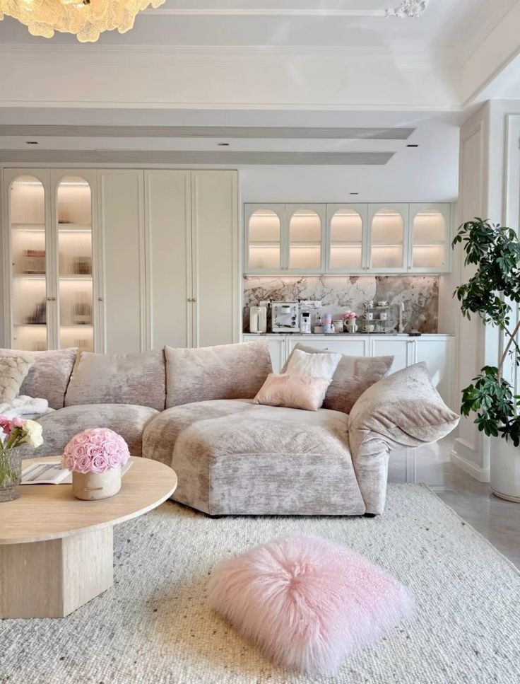 3b5d0c87-dd0a-43fb-ba01-c9a08960323c - Handy Home Chic modern living room with plush beige sofa, pink pillows, and coffee table. Bright, elegant decor with indoor plants and soft lighting.