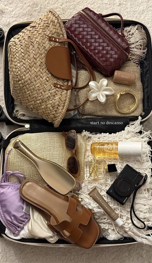 Screenshot Open suitcase with travel essentials: straw hat, woven bag, sunglasses, sandals, camera, perfume, and skincare. Ready for a stylish getaway! - Handy Home Open suitcase with travel essentials: straw hat, woven bag, sunglasses, sandals, camera, perfume, and skincare. Ready for a stylish getaway!