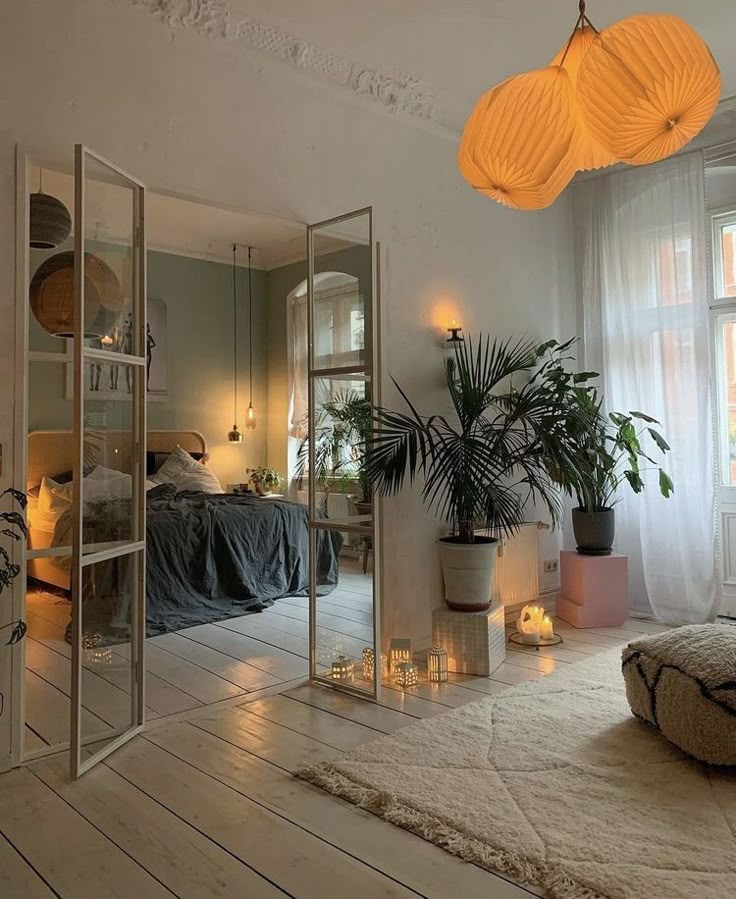 Cozy bedroom with ambient lighting, glass doors, and houseplants. Modern decor with soft textiles, white walls, and warm accents.
