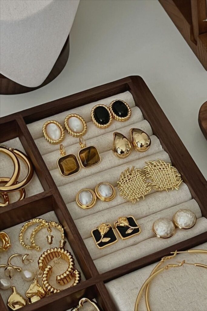 5ea1e233-3a3a-448d-b673-2e88f2f0e357 - Handy Home Gold and pearl earrings showcased in a wooden jewelry organizer, highlighting elegance and style.