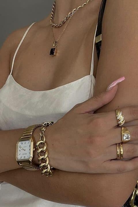 6ab44117-c33d-43ef-ac29-9f96b8d89202 - Handy Home Woman in a white dress with layered gold necklaces, watch, and rings, showcasing elegant jewelry and fashion accessories.