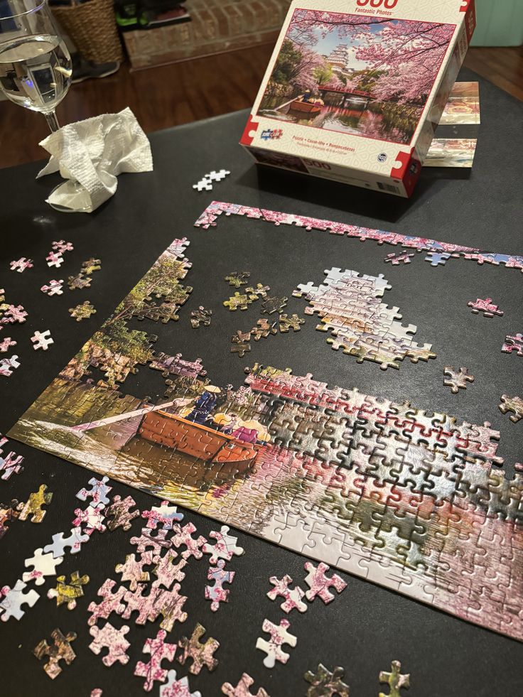 72b1472c-fb62-414d-bae8-336ef36a3913 - Handy Home Puzzle assembly in progress, featuring a scenic cherry blossom view. Wine glass and tissue add a cozy atmosphere.