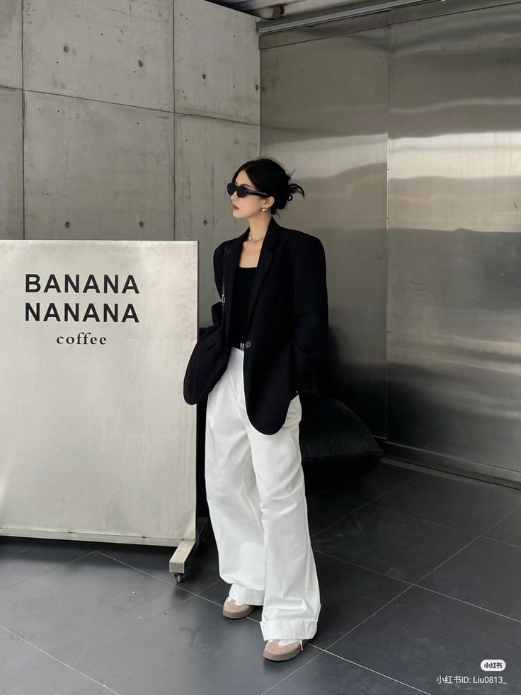 Casual wear - Handy Home Stylish woman in black blazer and white pants poses by Banana Nanan coffee shop with a modern industrial design background.