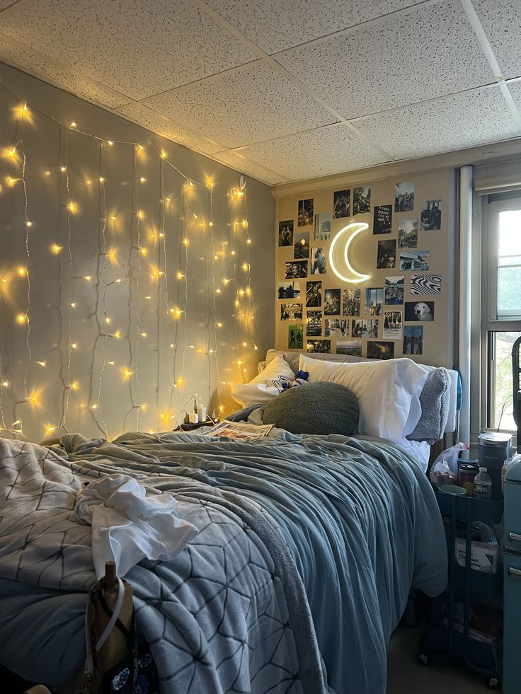 College Girl Dorm Room Cozy dorm room with fairy lights, a gallery wall, and a crescent moon lamp. Blue bedding adds to the inviting atmosphere. - Handy Home Cozy dorm room with fairy lights, a gallery wall, and a crescent moon lamp. Blue bedding adds to the inviting atmosphere.