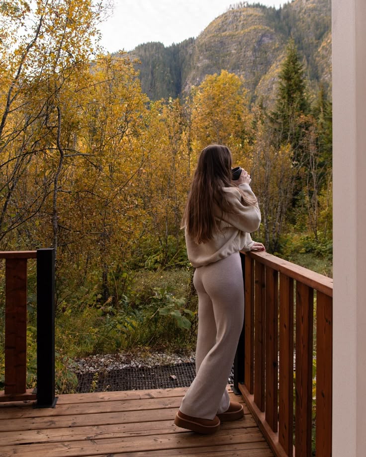 Cozy cabin season 🧸 alphamountainlodging Woman enjoying a hot drink on a wooden balcony, surrounded by autumn foliage and mountains. Cozy fall morning in nature. - Handy Home Woman enjoying a hot drink on a wooden balcony, surrounded by autumn foliage and mountains. Cozy fall morning in nature.