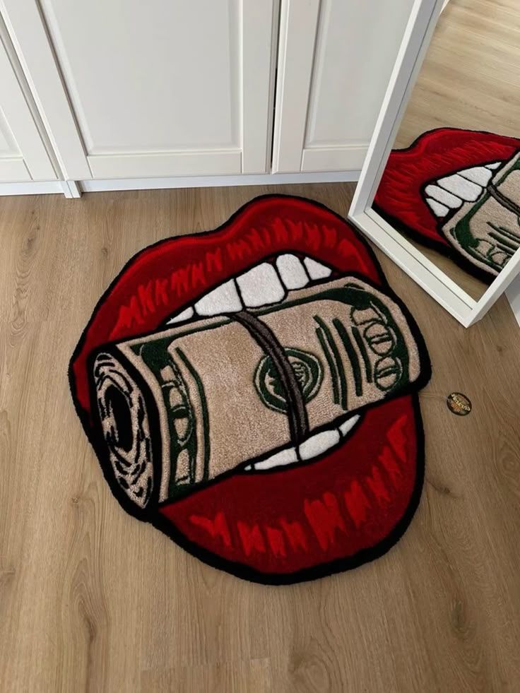 Rug with bold lips biting a rolled dollar bill design on a wooden floor, reflecting in a nearby mirror.