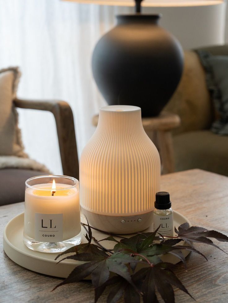 Electronic Diffuser - Handy Home Cozy setup with a lit candle, essential oil diffuser, and leaves on a wooden table, creating a warm, relaxing ambiance.