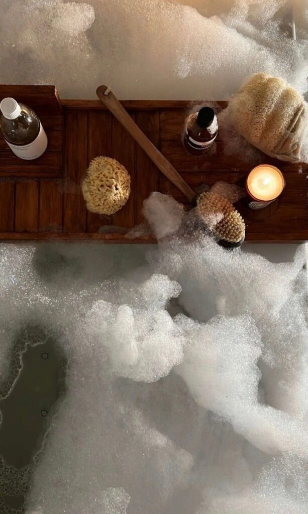 Glow-Up Wellness Transformation - Handy Home Luxurious bubble bath scene with wooden tray, lit candle, and spa essentials for a relaxing soak.
