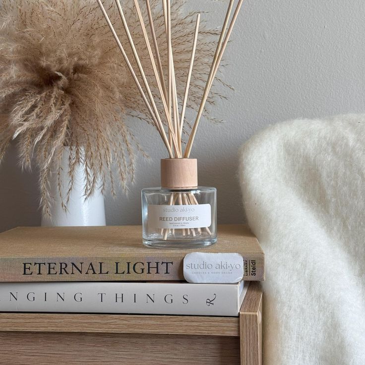 Pumpkin Chai Reed Diffuser _ Autumn Fall Cosy Season _ Autumn Hygge Scented Space _ Cozy Fall Autumn Home _ Pumpkin Season _ Home Gifts - Handy Home Reed diffuser on books with pampas grass and a cozy blanket, creating a calming, aromatic home decor vibe.