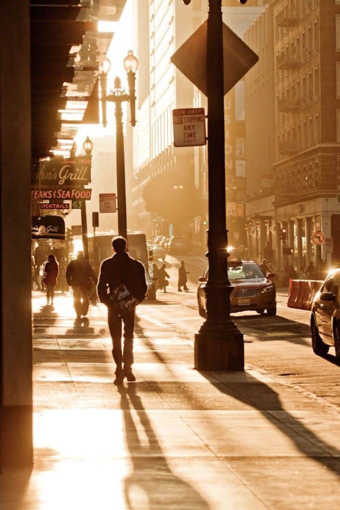 Sunset San Francisco SF Street sun orange - Handy Home Urban street scene at sunset with silhouettes of people walking and cars, creating long shadows and warm golden light.