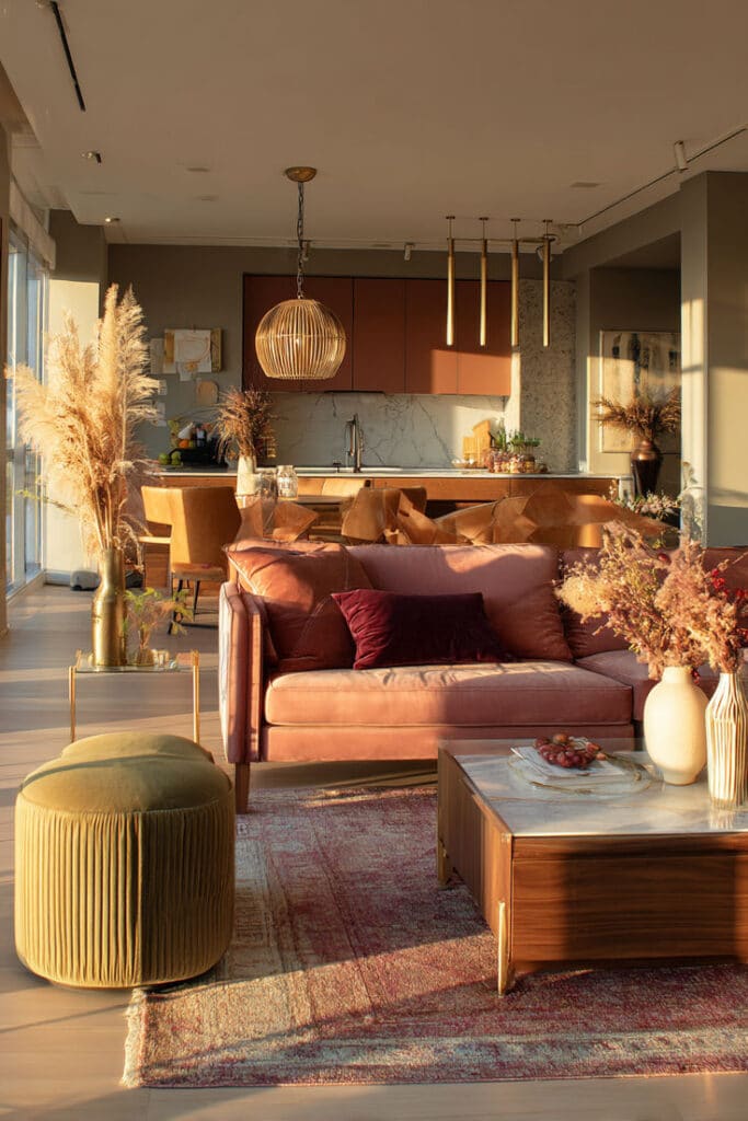 Warm Sunset Living Room Velvet Sofa Golden Hour Interior Inspiration - Handy Home Modern living room with pink sofa, elegant decor, and kitchen in warm lighting. Cozy, stylish interior design.
