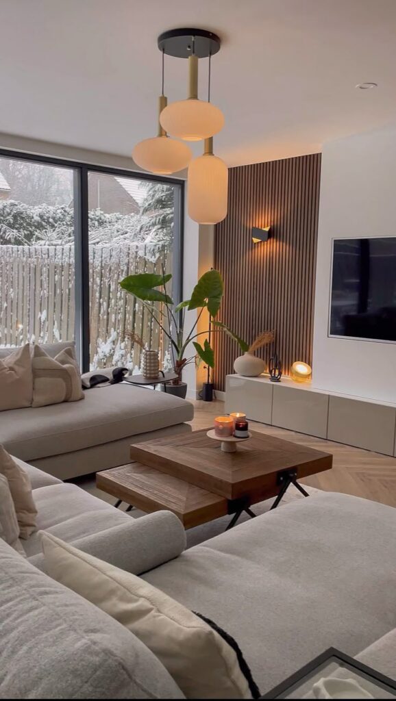 c579cbd5-34d8-457f-8a91-1a0ef770c9f1 - Handy Home Modern living room with cozy sectional sofa, wooden coffee table, stylish pendant lights, and snowy view through large windows.