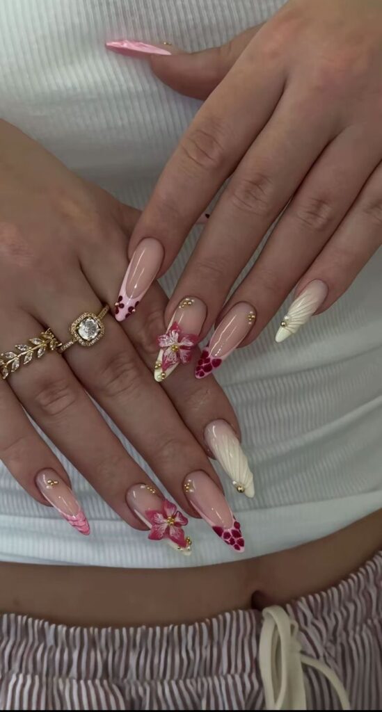 dfbf5a91-ea85-4ccf-9949-23f1571b2732 - Handy Home Elegant floral nail art with pink and white designs, gold accents, and standout rings, perfect for stylish manicure inspiration.
