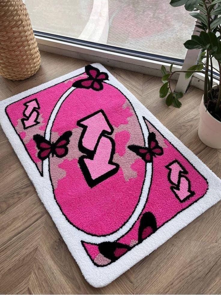 Bright pink rug with reverse card and butterfly design, placed on wooden floor, near plants, ideal for playful decor.