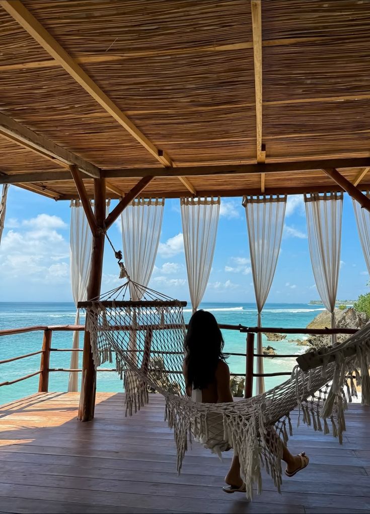 sabbu_balami - Handy Home Woman relaxing on a hammock overlooking a serene ocean view from a bamboo deck.