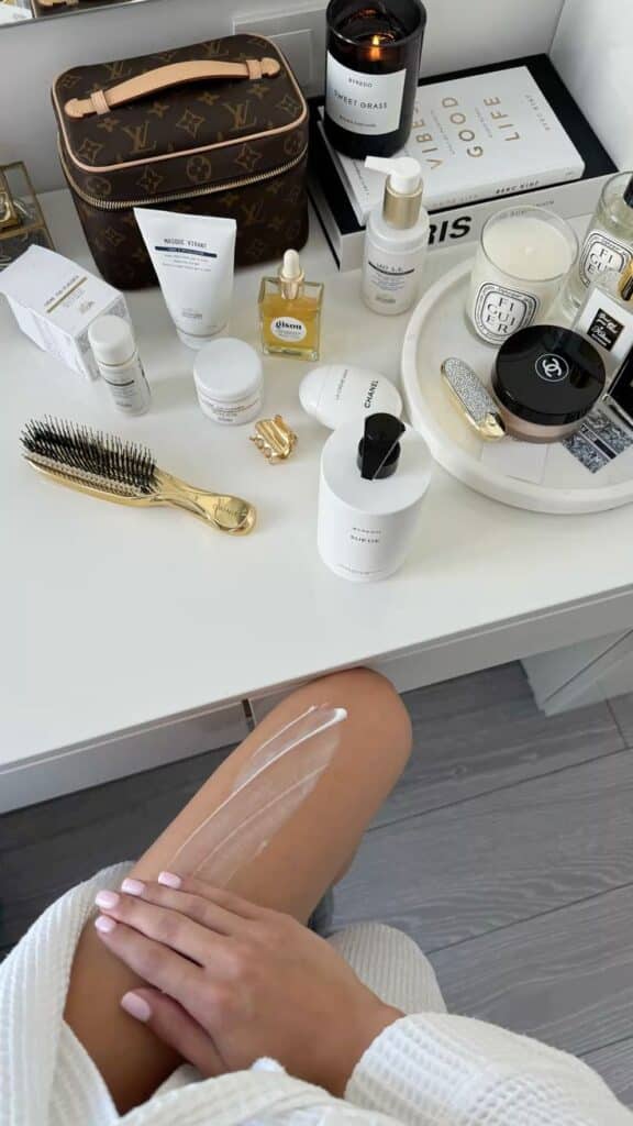 selfcare beautyblog skincare - Handy Home Luxurious skincare products and a hand applying cream, featuring candles and a designer toiletry bag on a vanity.