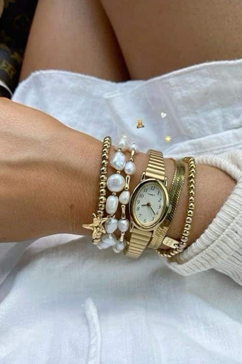 timeless jewelry - Handy Home Gold watch with pearl and beaded bracelets on wrist, white sleeve in background, stylish and elegant accessory display.