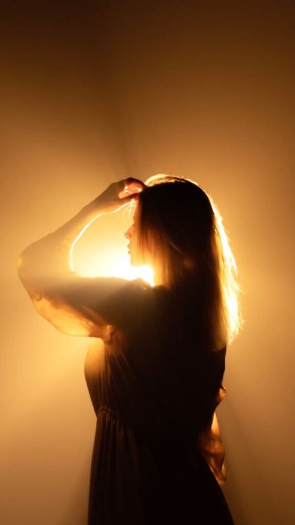Silhouetted woman in a dress, illuminated by warm backlighting, touches her head in a dramatic, artistic pose. - Handy Home Silhouetted woman in a dress, illuminated by warm backlighting, touches her head in a dramatic, artistic pose.