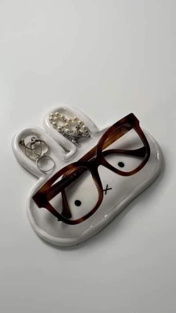 Ceramic bunny-shaped tray with glasses and jewelry, organized on a white background for a cute and functional decor piece.