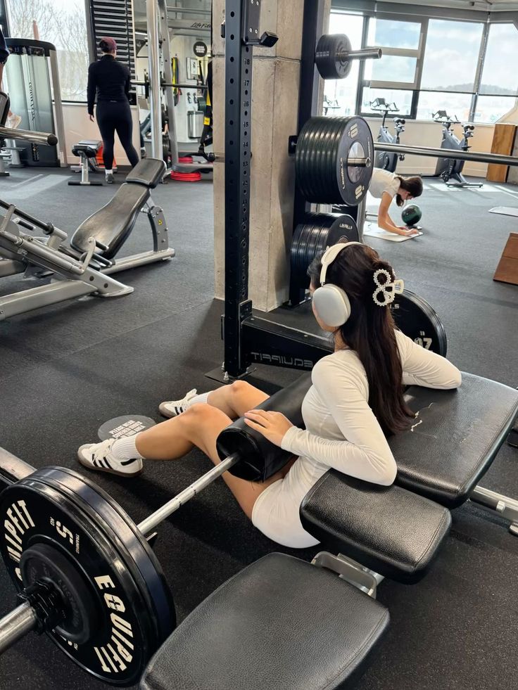 063264b9-5c16-4283-a6f8-6686d496570f Woman in gym wearing headphones, performing hip thrusts with weights. Fitness workout in modern gym setting. - Handy Home Woman in gym wearing headphones, performing hip thrusts with weights. Fitness workout in modern gym setting.