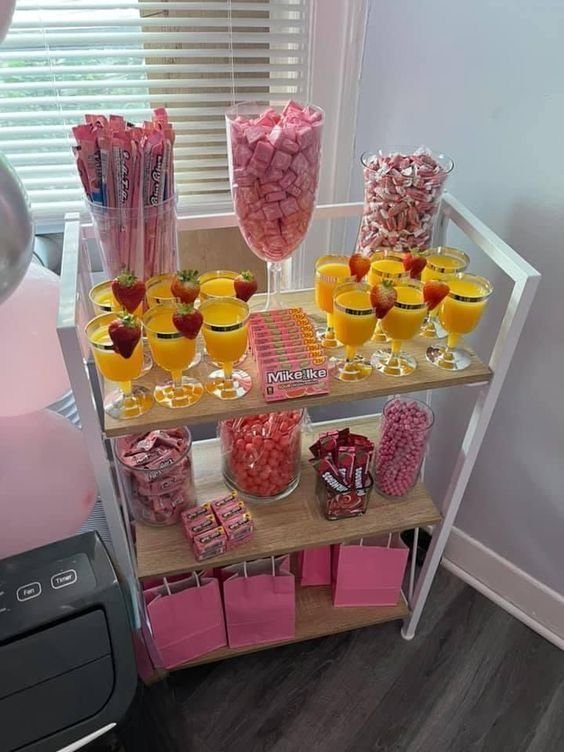 2bf1e060-fbf9-44d1-bfda-ff5476bb4d6b Candy and drink bar setup with pink and orange sweets, glasses with orange liquid and strawberries, and pink gift bags. - Handy Home Candy and drink bar setup with pink and orange sweets, glasses with orange liquid and strawberries, and pink gift bags. Sleepover Ideas