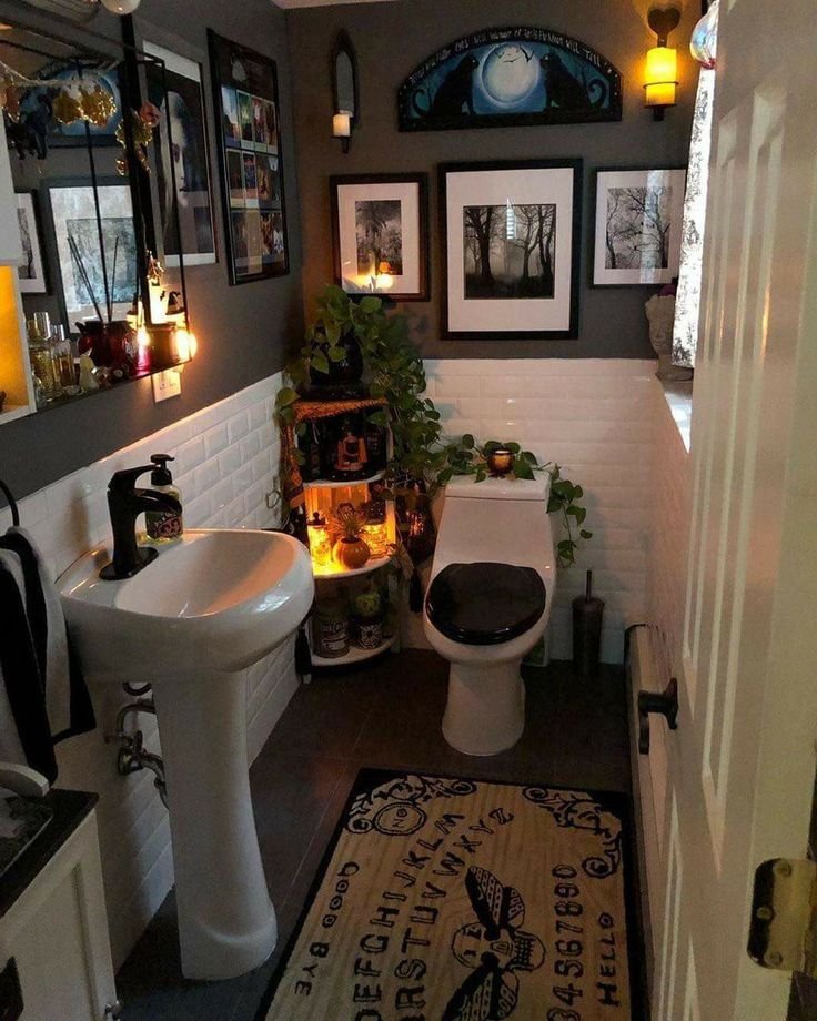 Dimly lit bathroom with dark decor, Ouija board rug, plants, and candles creating a mysterious, cozy atmosphere.
