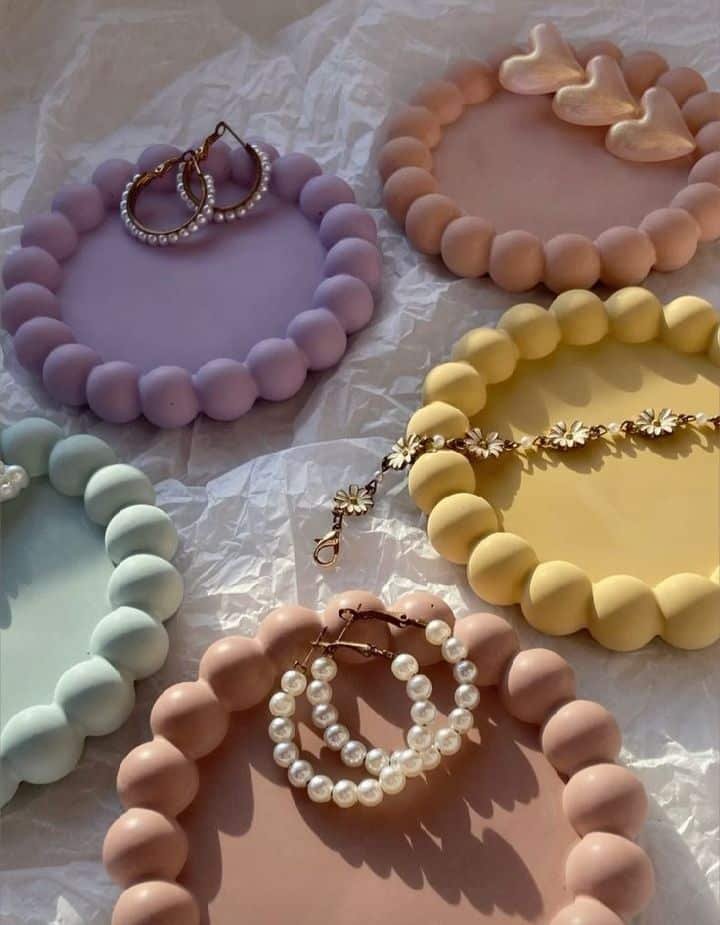 Colorful bead trays with pearl earrings and heart decor on crumpled paper in soft sunlight. Perfect for stylish organizing.