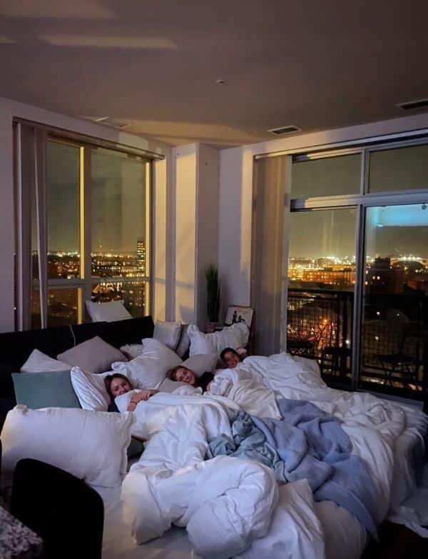 77969235-03b3-4945-beea-2b03ae70a28f Cozy night in with friends on a bed by the window, overlooking a stunning cityscape at night. - Handy Home Cozy night in with friends on a bed by the window, overlooking a stunning cityscape at night.