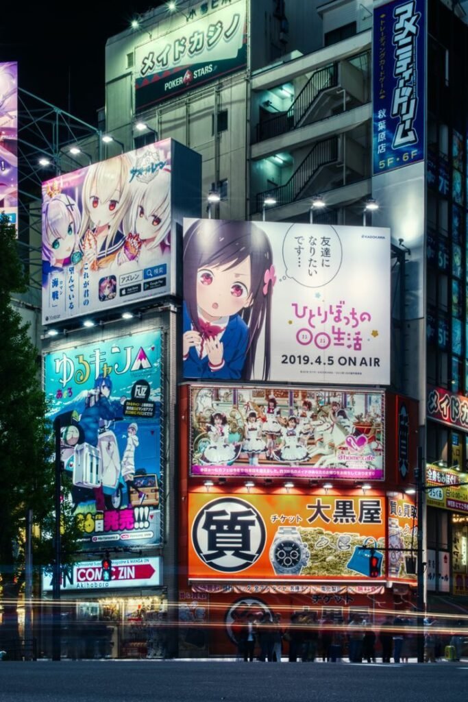 Vibrant anime and maid café billboards light up an urban street at night in Akihabara, Tokyo, capturing Japanese pop culture.