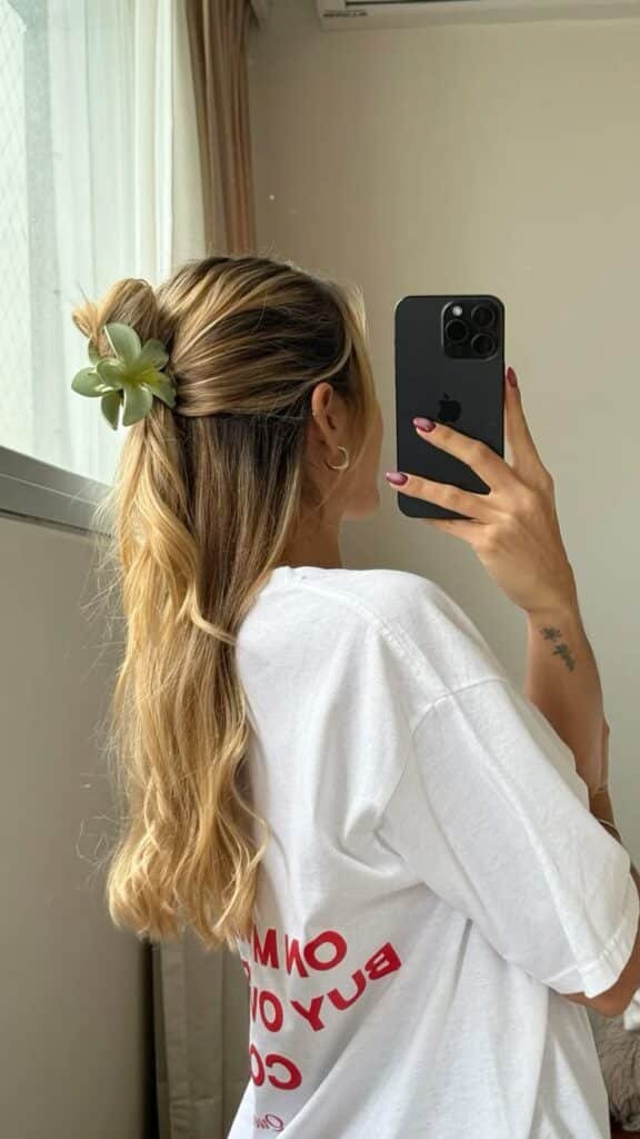 Aesthetic hairstyle ✨ Woman with long blonde hair styled with a green flower clip, taking a mirror selfie in a white t-shirt. - Handy Home Woman with long blonde hair styled with a green flower clip, taking a mirror selfie in a white t-shirt.
