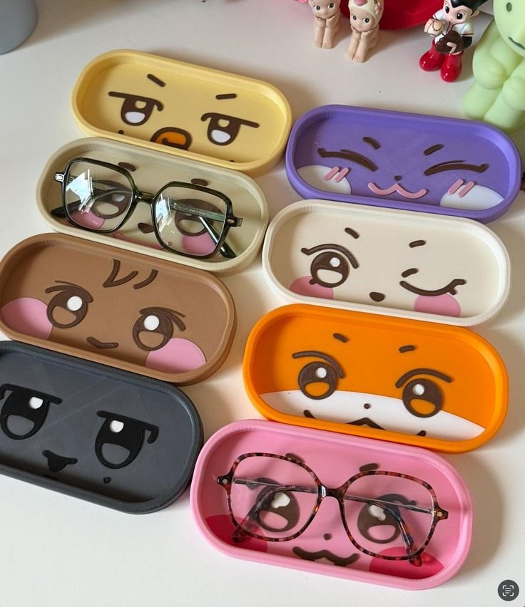Colorful cartoon face trays with stylish eyeglasses, surrounded by cute figures. Fun and playful design for organizing eyewear.